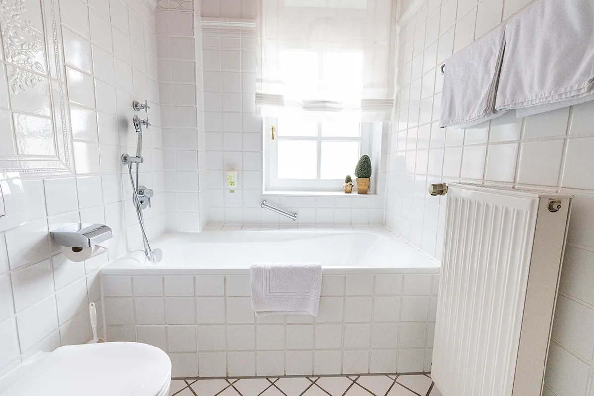 Weiß gefliestes Bad mit Badewanne