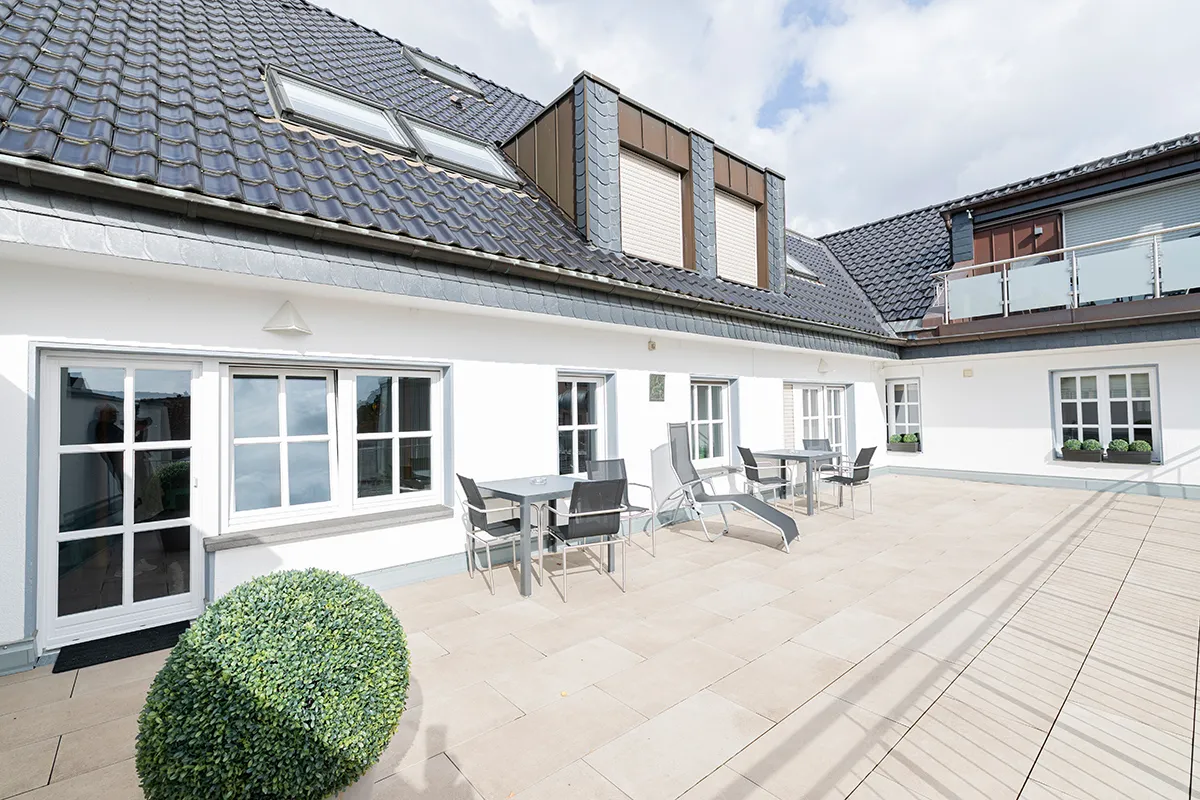 Dachterrasse mit Tischen und Liegestühlen